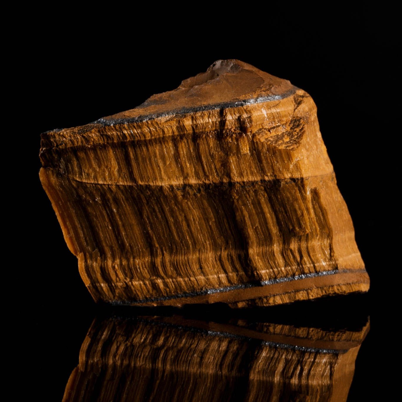 Raw, uncut tiger eye stone showing the natural mineral source. Aurum Brothers.